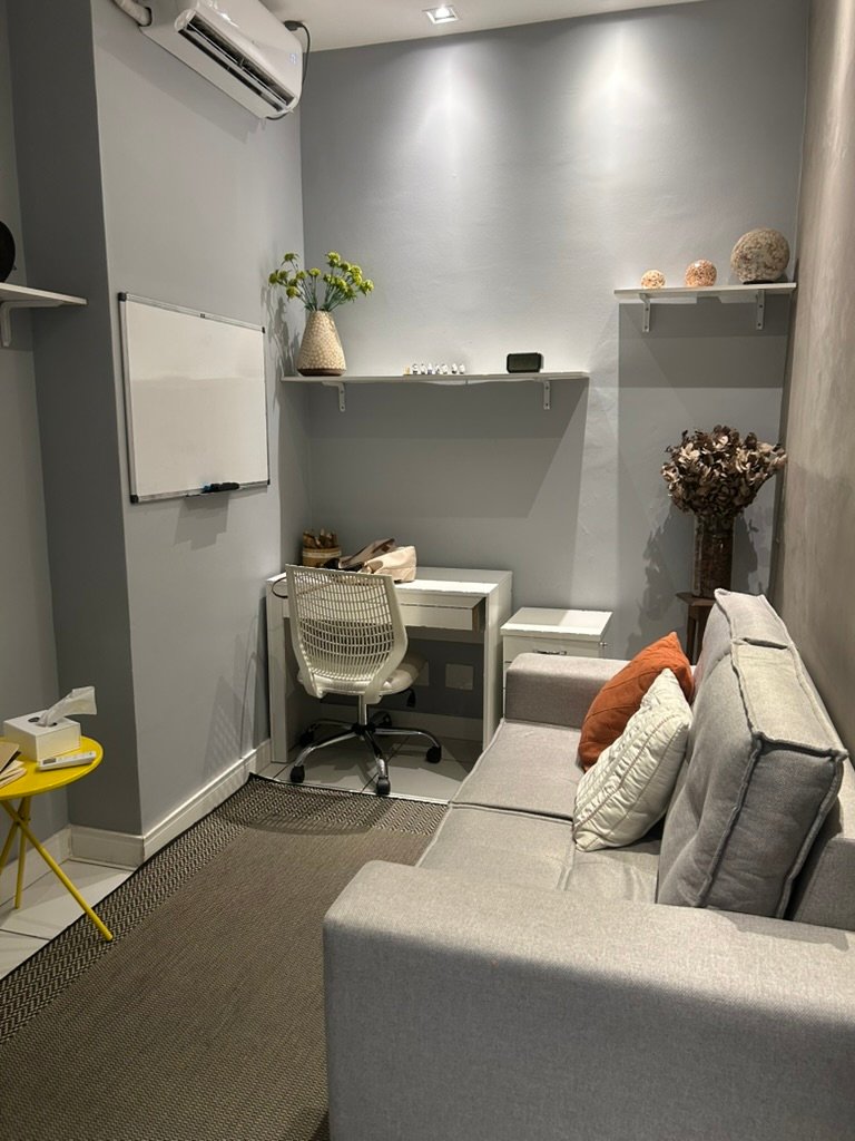 Sala de atendimento do consultório, com sofá, mesa de trabalho e decoração.